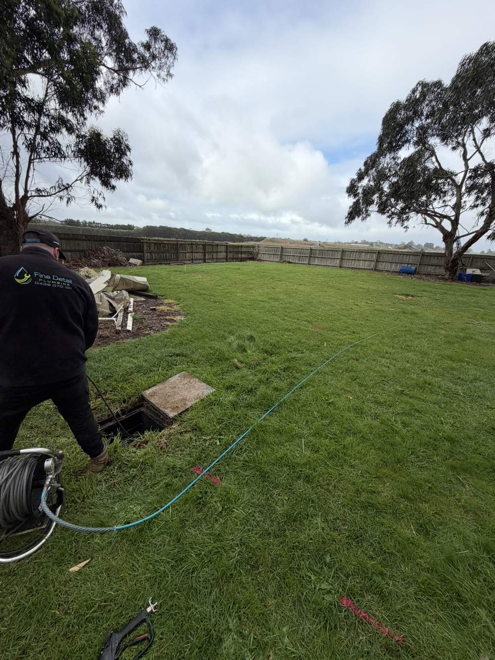 Fine Detail Plumbing technician clearing a blocked stormwater drain with hydro jetting hose in a Clyde backyard