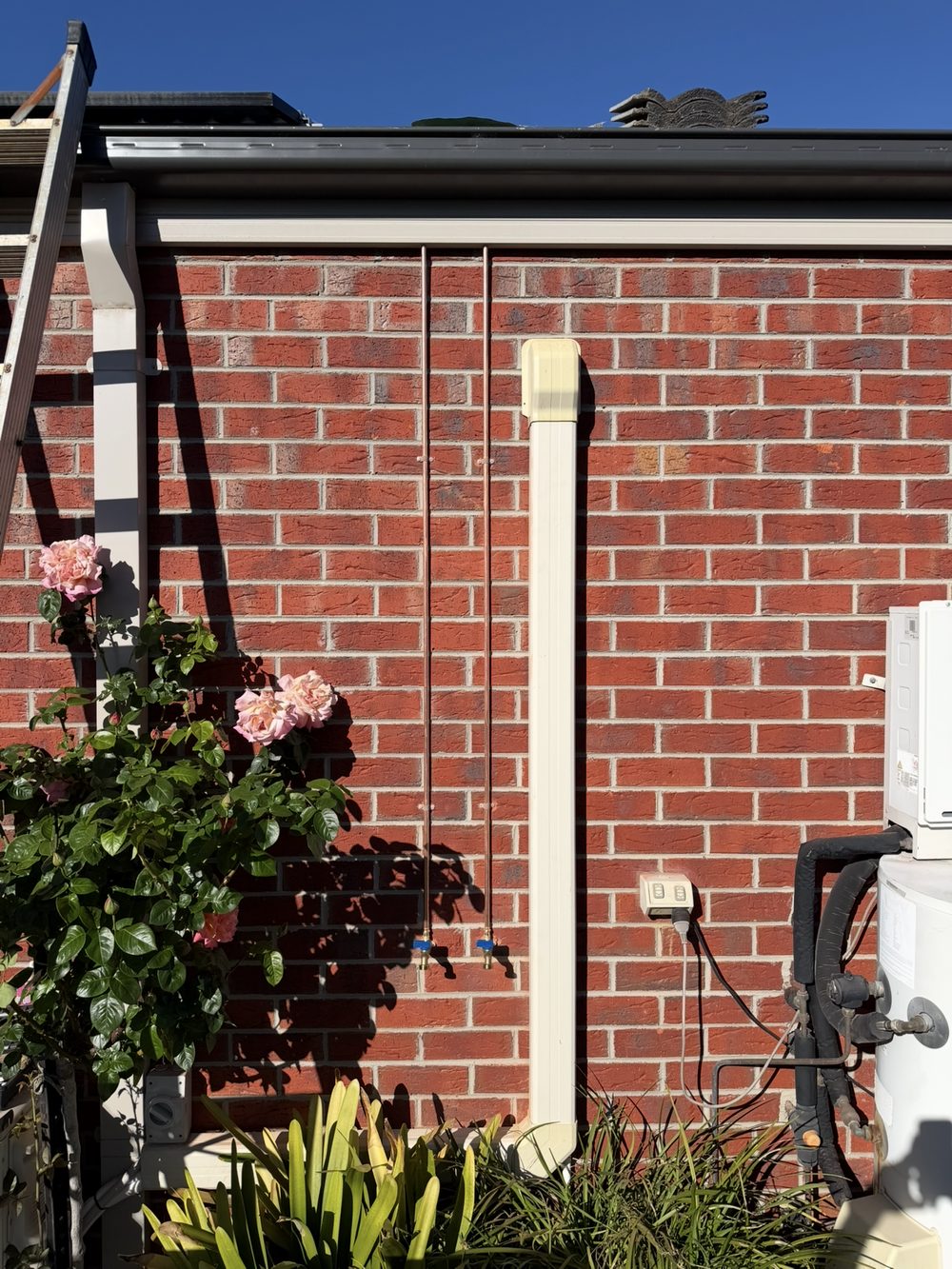 Two outdoor garden taps installed on separate copper water lines against a brick wall in Knoxfield
